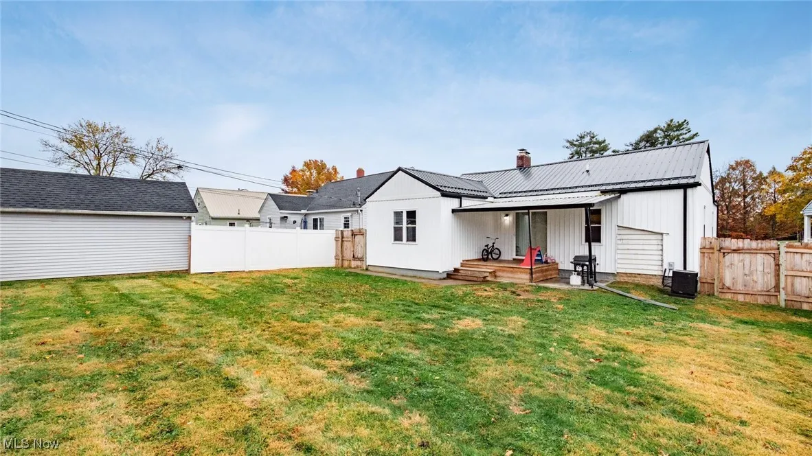 Back of house with a chimney, a metal roof, board and batten siding, a fenced backyard, and a patio