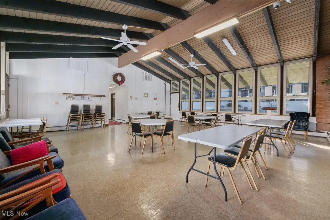 Dining space with light flooring, high vaulted ceiling, ceiling fan, healthy amount of natural light, and a baseboard radiator