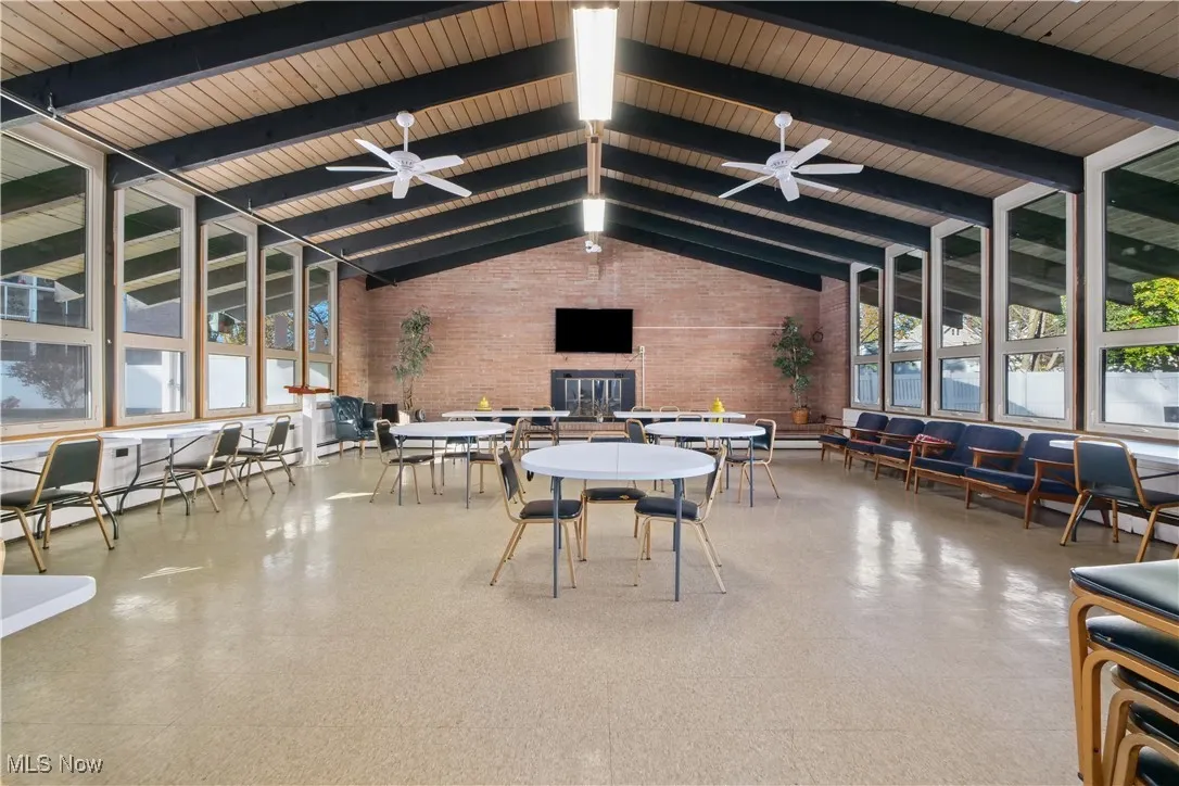 Dining room featuring light flooring, high vaulted ceiling, beam ceiling, brick wall, and a baseboard heating unit