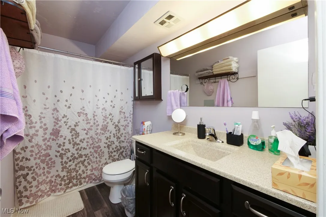 Bathroom with a shower with shower curtain, vanity, and dark wood-style flooring