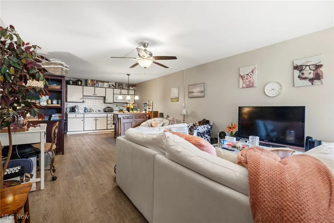 Living room featuring dark wood-style flooring and a ceiling fan