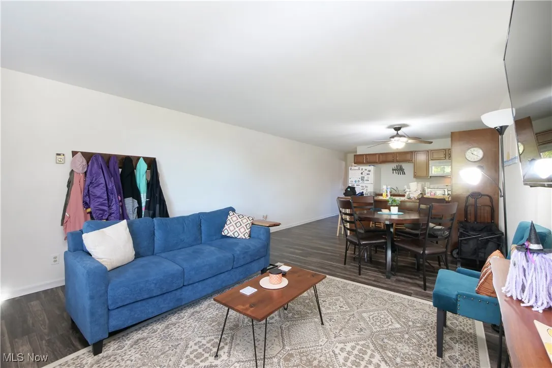Living area featuring dark wood-type flooring and a ceiling fan