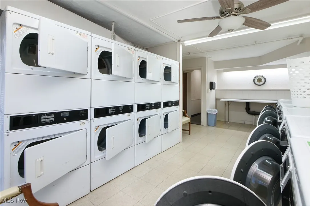 Shared laundry featuring stacked washing machine and dryer and a ceiling fan