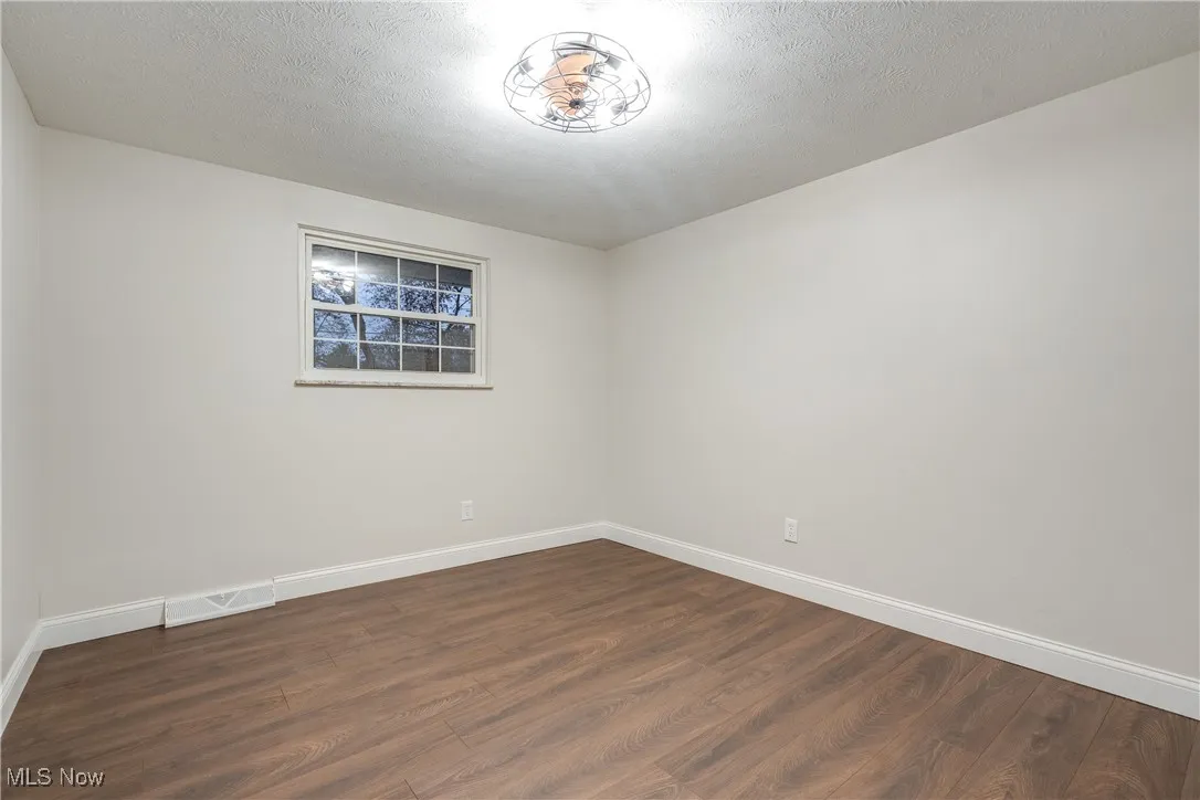 Unfurnished room with dark wood-style floors and a textured ceiling