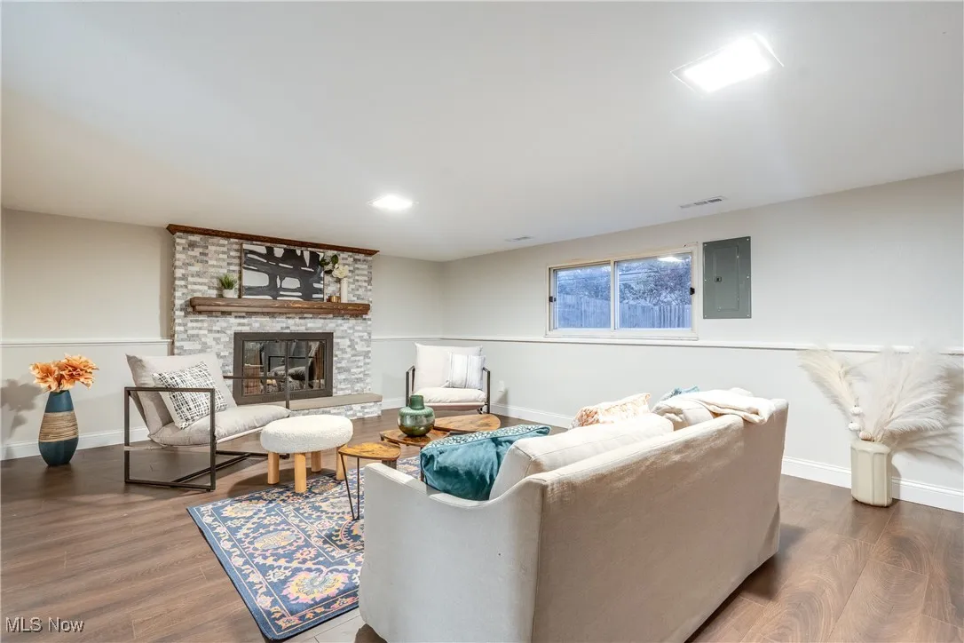Living area with dark wood-style floors, and a large stone fireplace