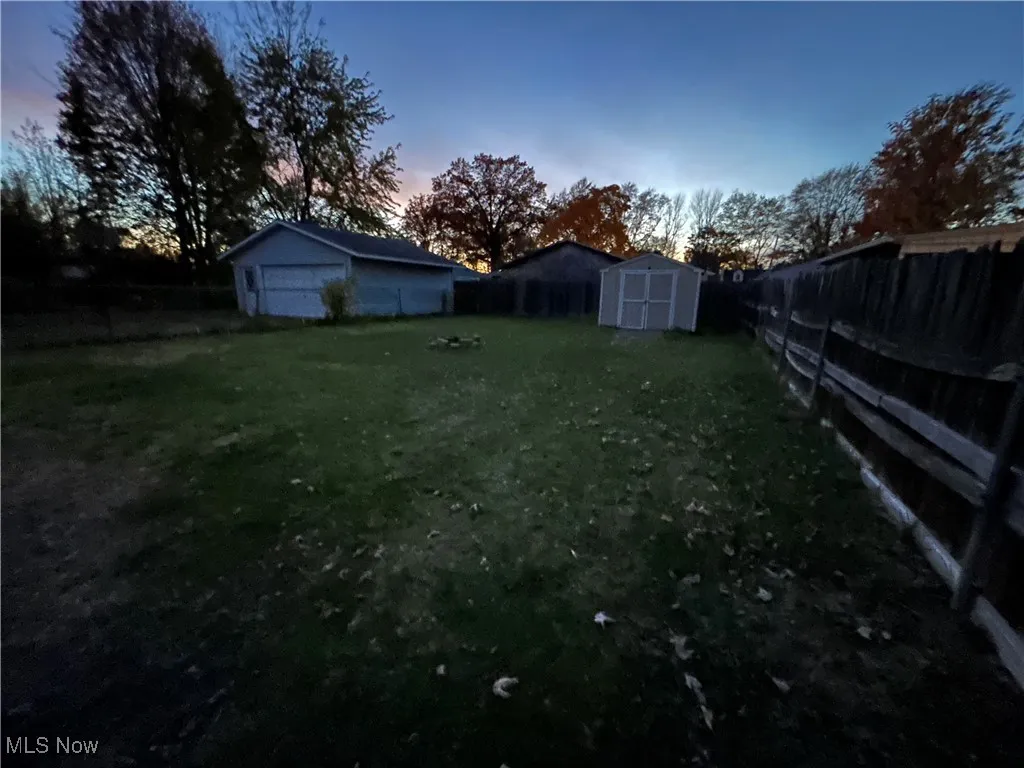 Yard at dusk with a fenced backyard and a storage shed
