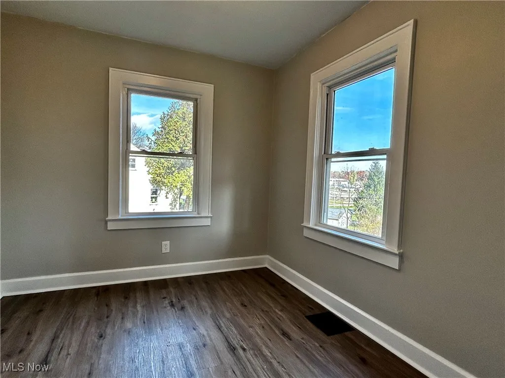 Spare room featuring dark wood-type flooring and plenty of natural light