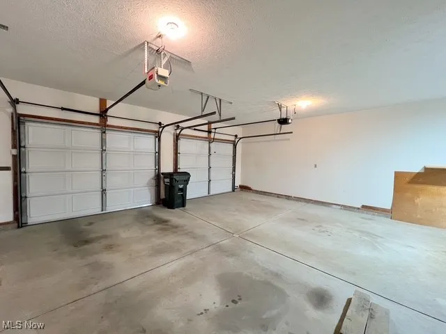 Garage featuring a garage door opener and baseboards