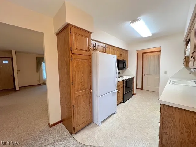 Kitchen featuring white appliances, light countertops, and brown cabinetry