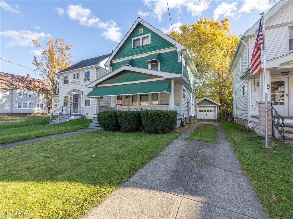 View of front of home with an outbuilding, a front lawn, a garage, covered porch, and driveway