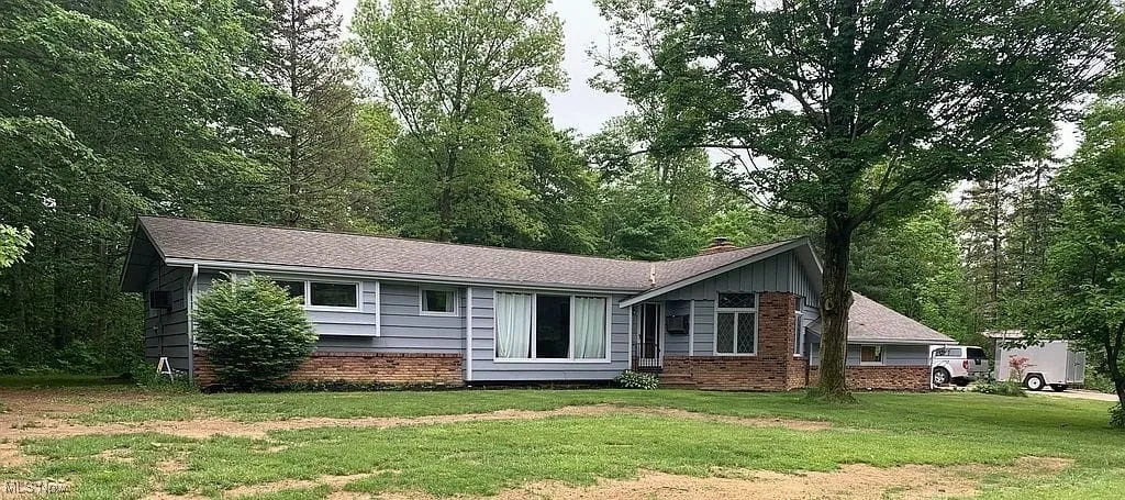 Ranch-style house featuring brick siding, a front yard, a chimney, and roof with shingles