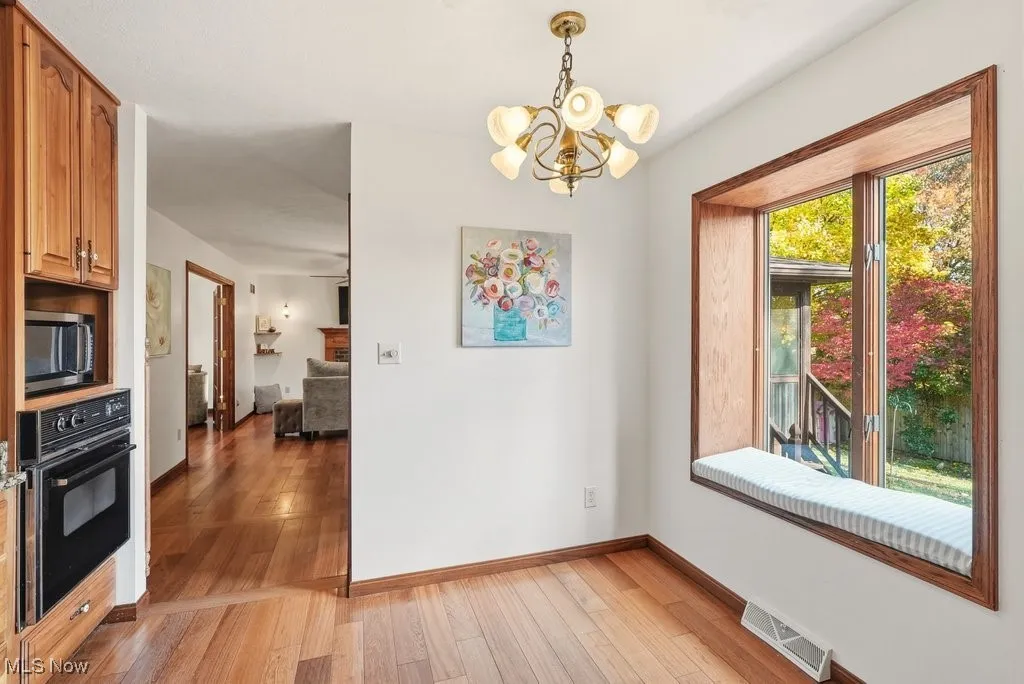 Unfurnished dining area featuring light wood-type flooring and a chandelier