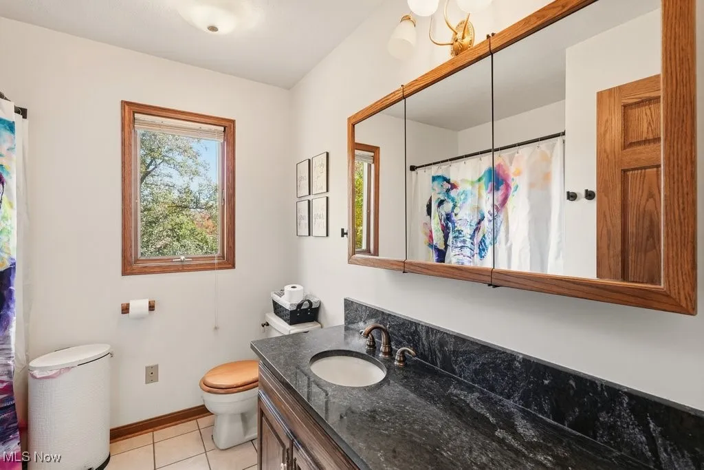 Bathroom with light tile patterned floors, vanity, and curtained shower