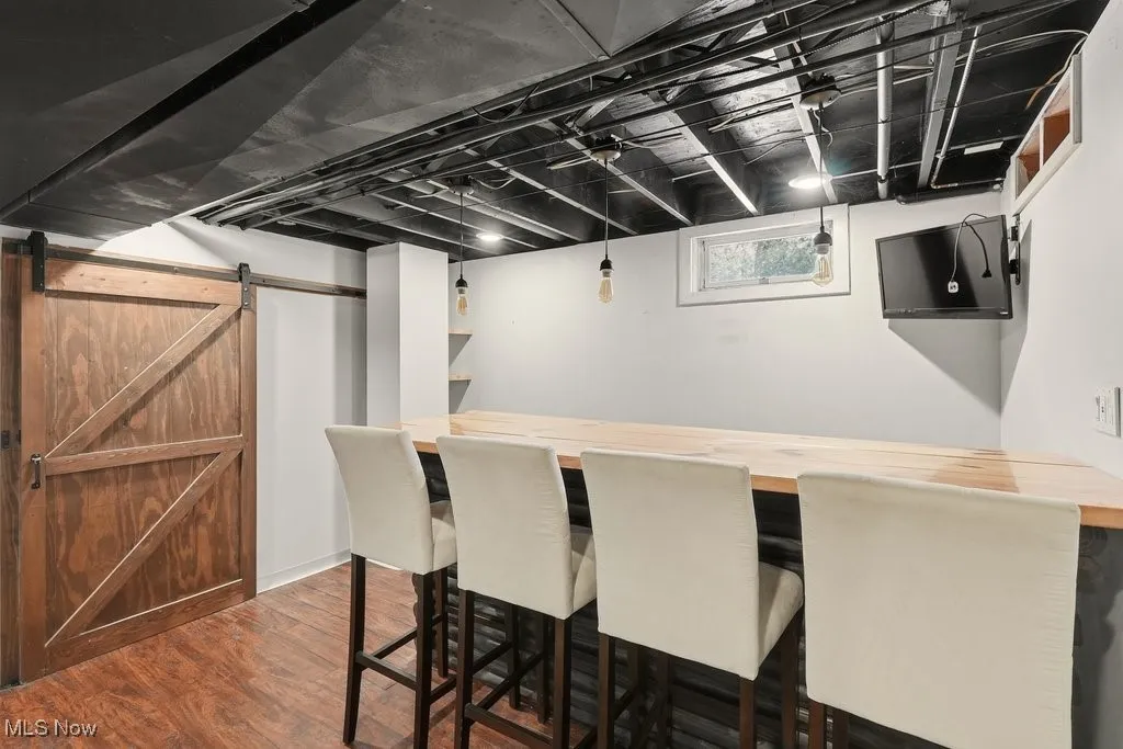 Bar with butcher block counters, dark wood-type flooring, pendant lighting, and a barn door