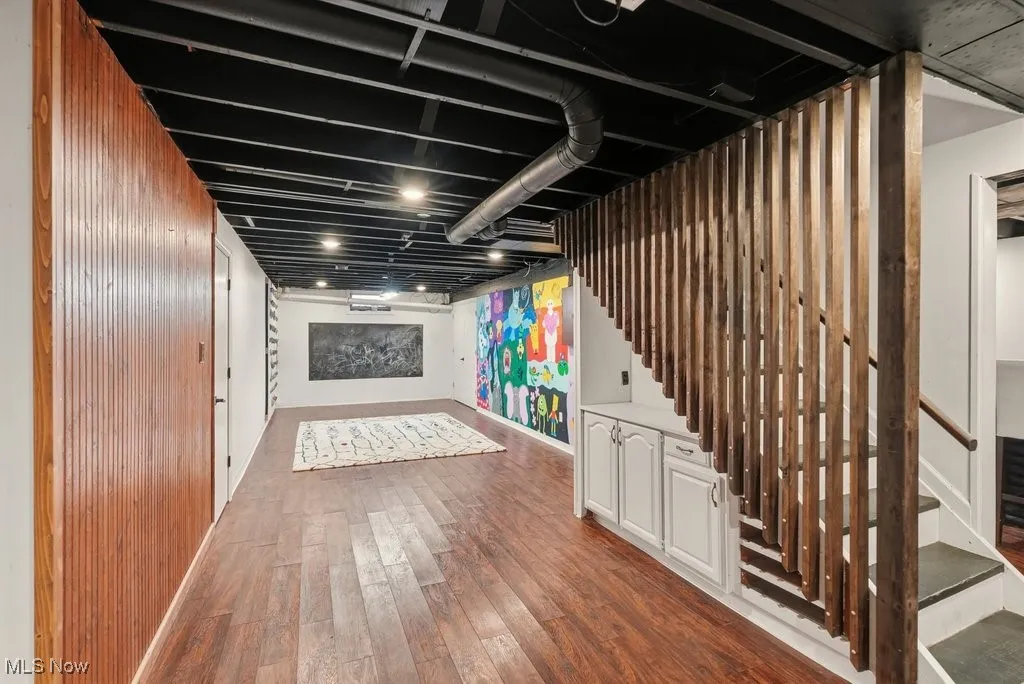 Finished below grade area featuring stairs and dark wood-style flooring