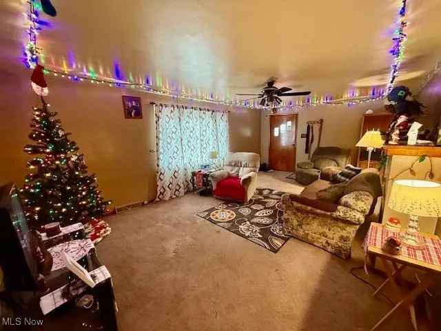 Carpeted living room featuring rail lighting and ceiling fan