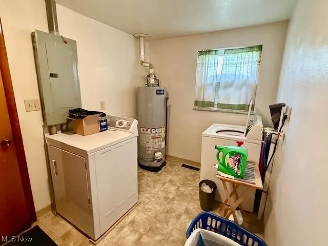 Laundry room featuring electric panel, gas water heater, and washing machine and clothes dryer