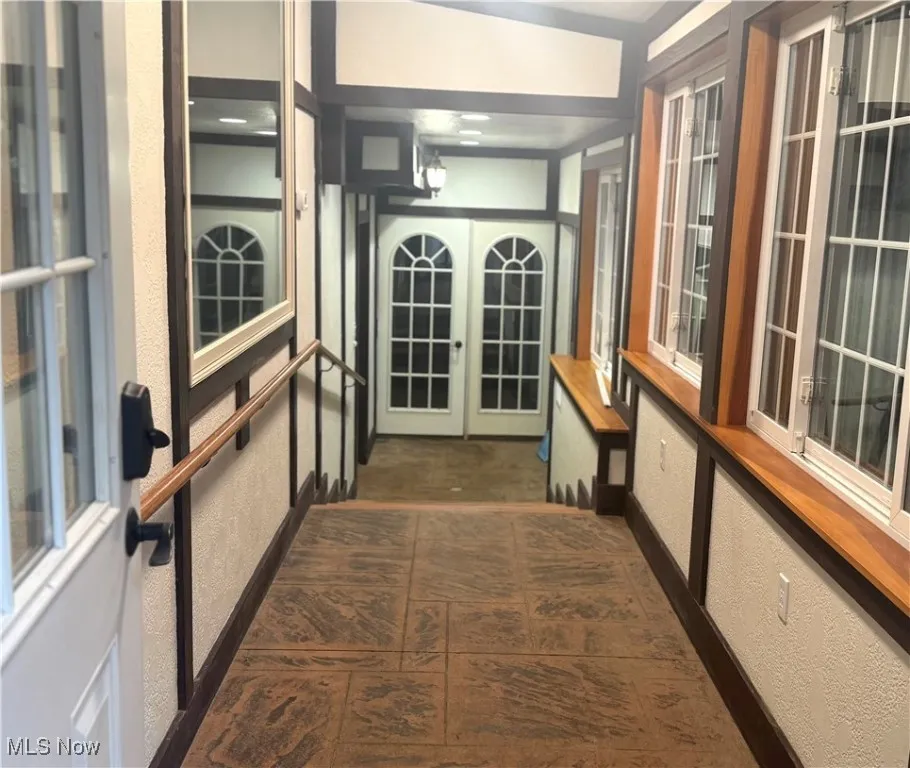 Corridor with a textured wall and french doors