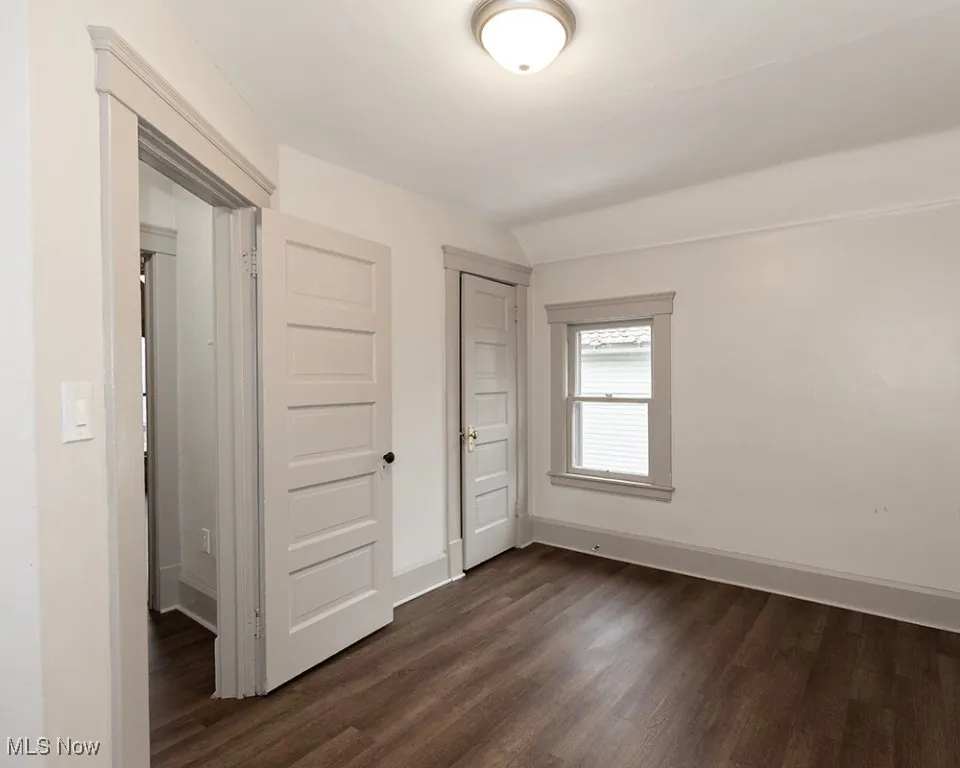 Unfurnished bedroom featuring dark wood finished floors and a closet