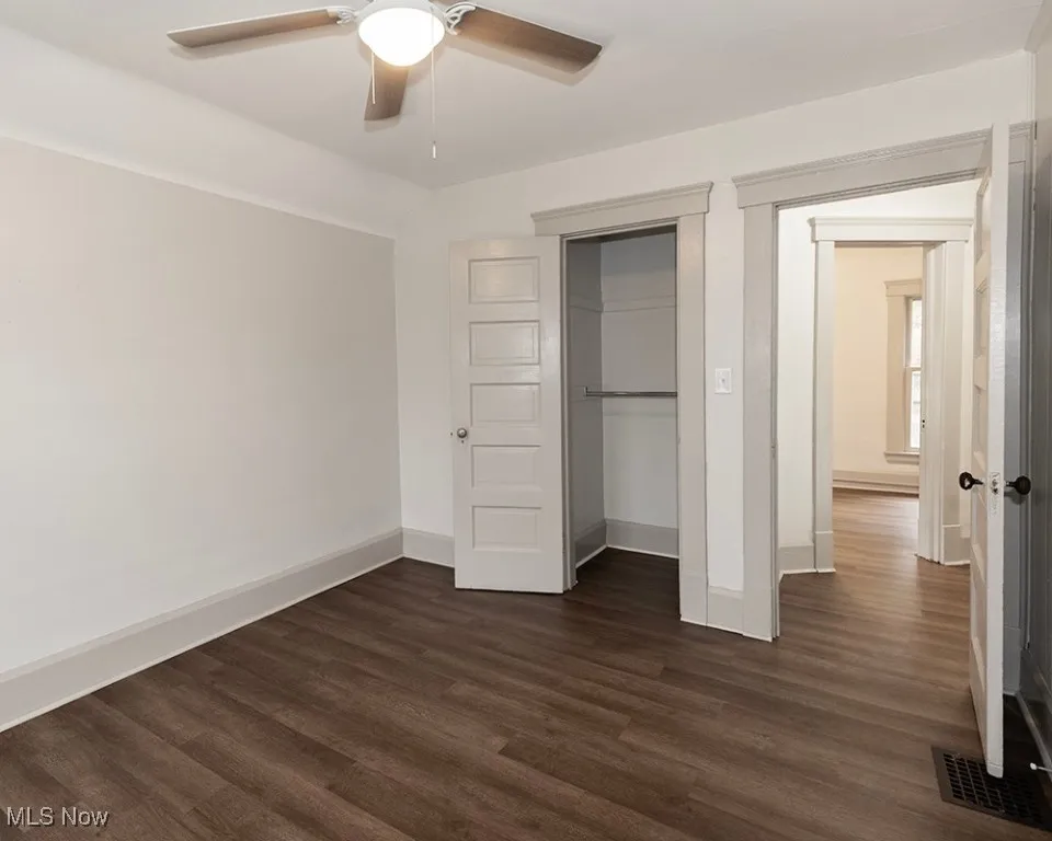 Unfurnished bedroom featuring dark wood-type flooring, a closet, and ceiling fan