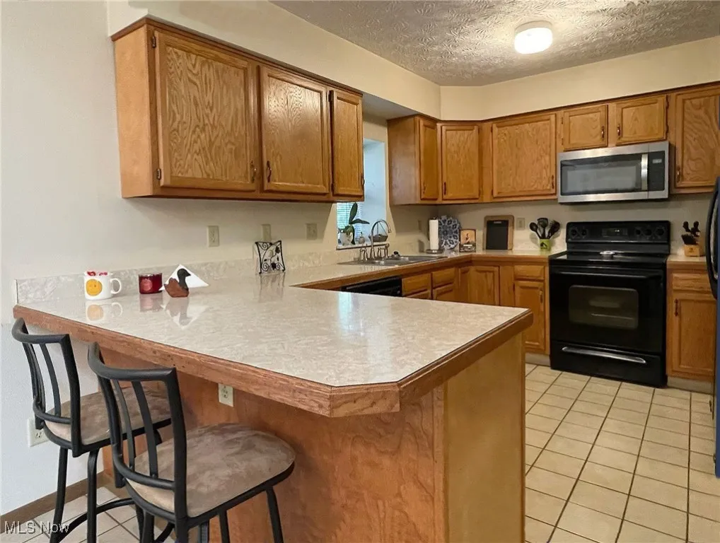 The kitchen has oak cabinety, a convenient breakfast bar/peninsula and ceramic tile flooring.