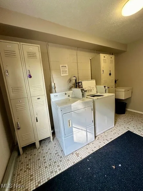 Clothes washing area featuring a textured ceiling, sink, and independent washer and dryer