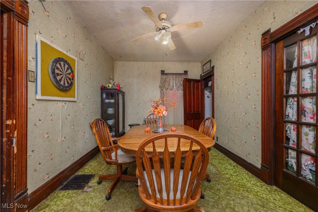 Dining space with a textured ceiling, wallpapered walls, and ceiling fan