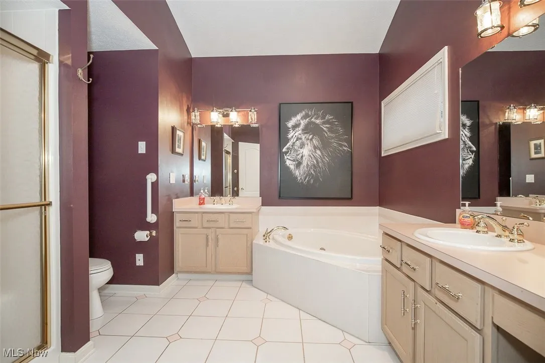 Bathroom with two vanities, light tile patterned floors, a garden tub, and a stall shower