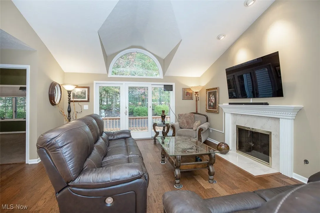 Living room featuring lofted ceiling, dark wood-type flooring, french doors, and a fireplace
