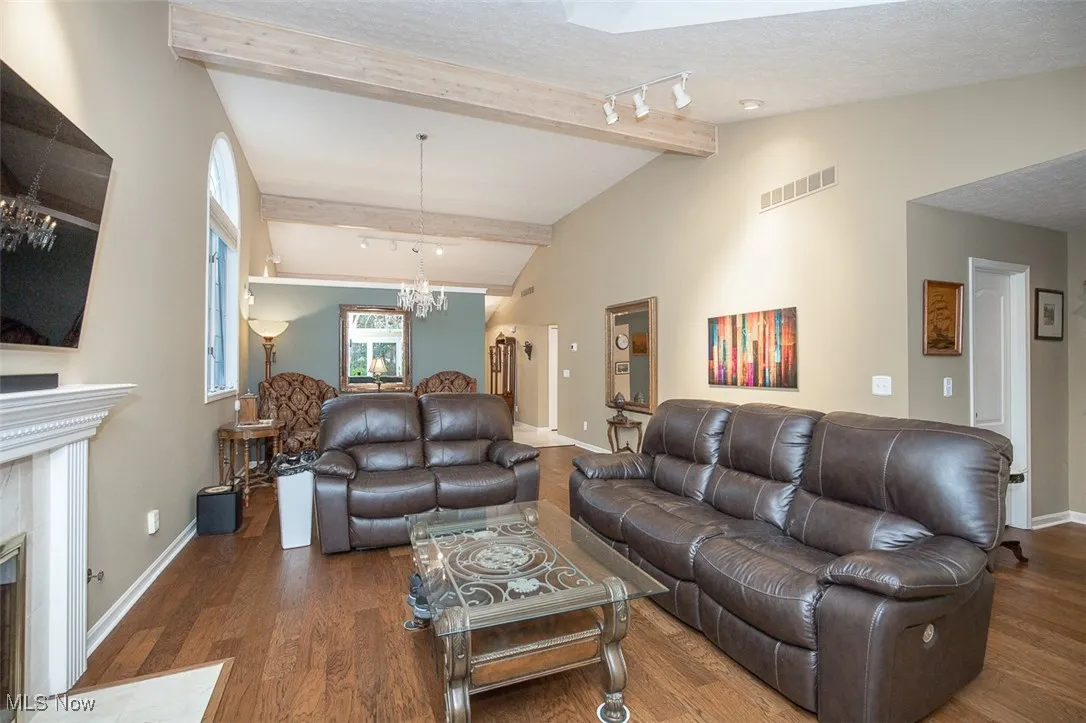 Living room with rail lighting, wood finished floors, a fireplace, a chandelier, and a textured ceiling