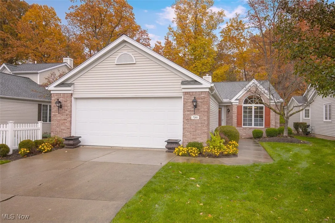Single story home with a chimney, concrete driveway, brick siding, and a garage