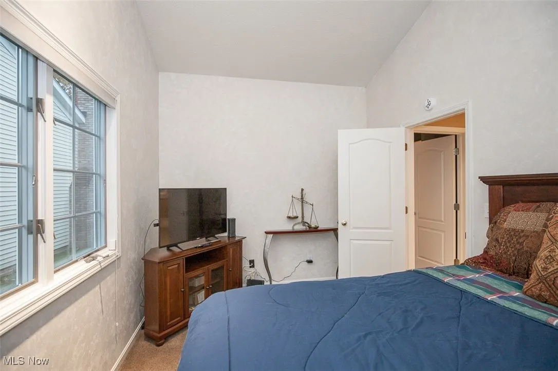 Bedroom with carpet floors and vaulted ceiling