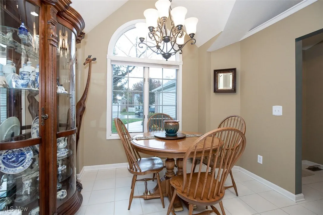 Dining area with a chandelier, vaulted ceiling, and light tile patterned floors