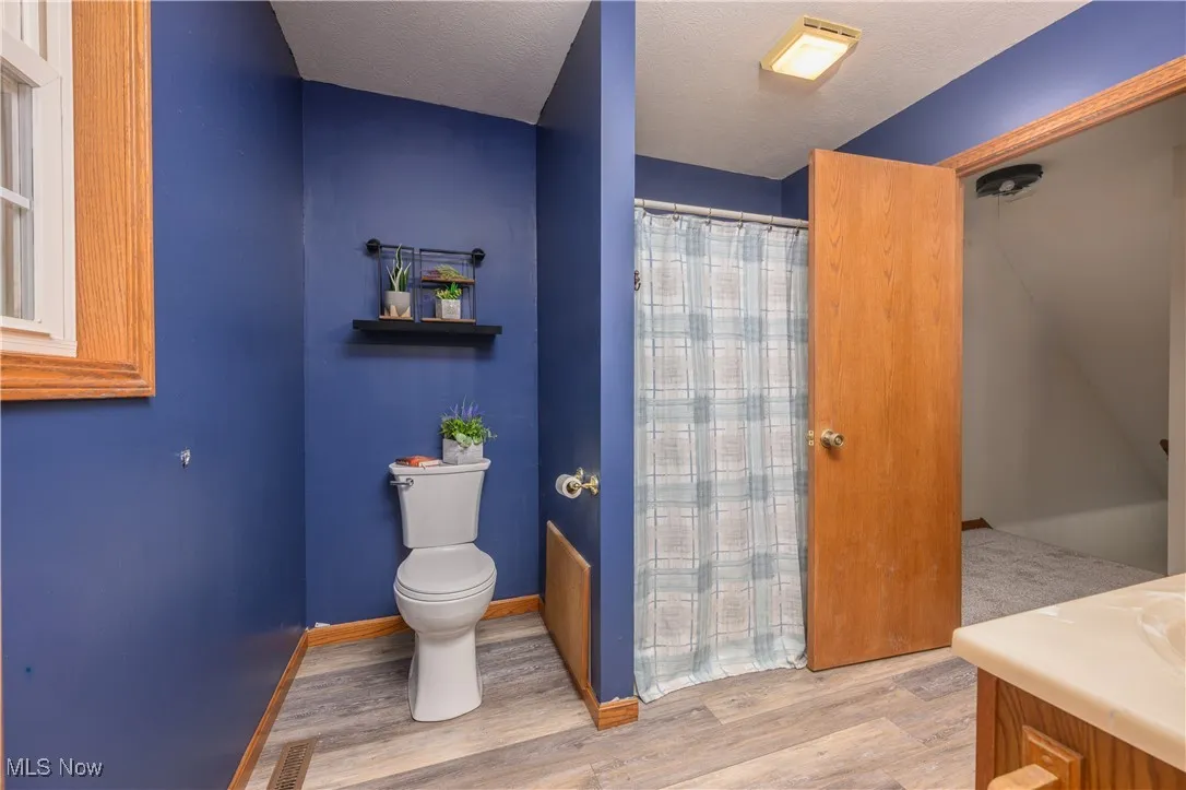 Bathroom with a shower with shower curtain, light wood-style flooring, vanity, and a textured ceiling