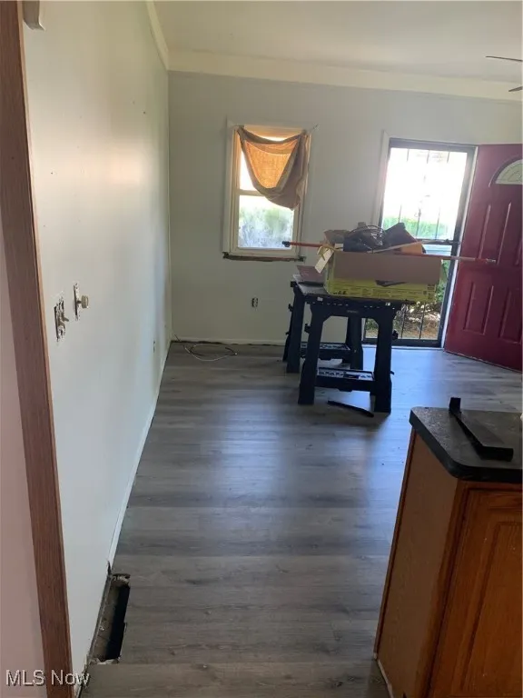 Dining area with healthy amount of natural light, dark wood-style flooring, and crown molding