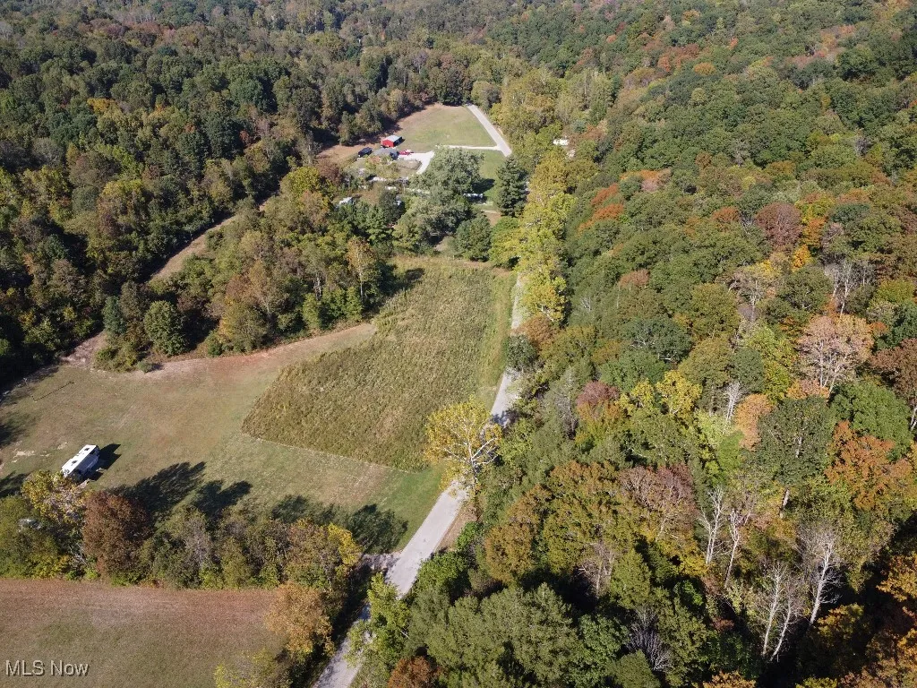 Aerial view of property and surrounding area with a heavily wooded area
