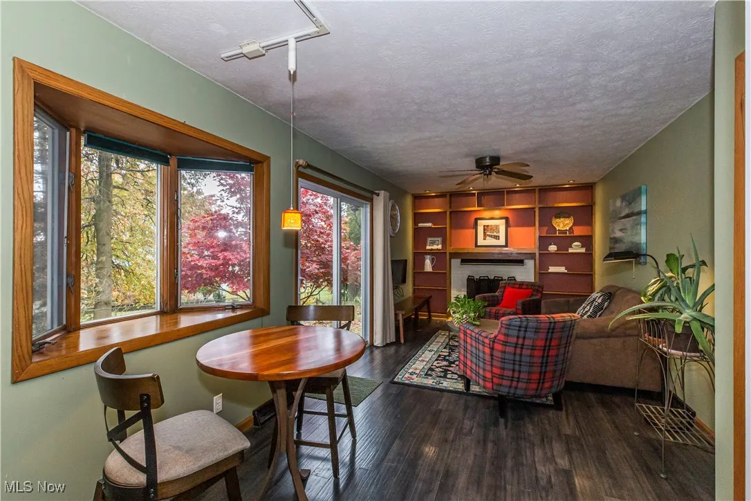 Living area with a fireplace, laminate type flooring, a textured ceiling, ceiling fan, and built in features