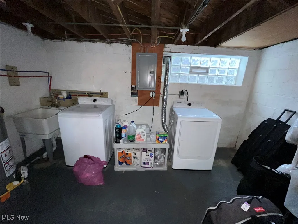 Laundry area featuring electric panel, separate washer and dryer, and gas water heater