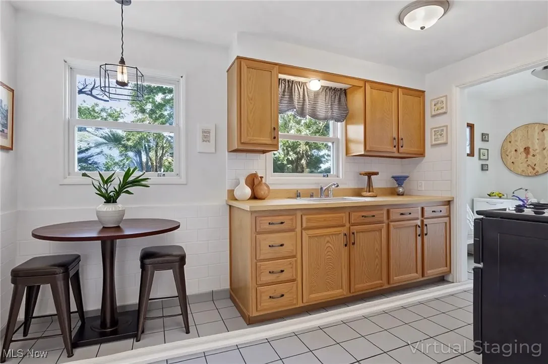 Kitchen with light countertops, tasteful backsplash, hanging light fixtures, wainscoting, and light tile patterned floors