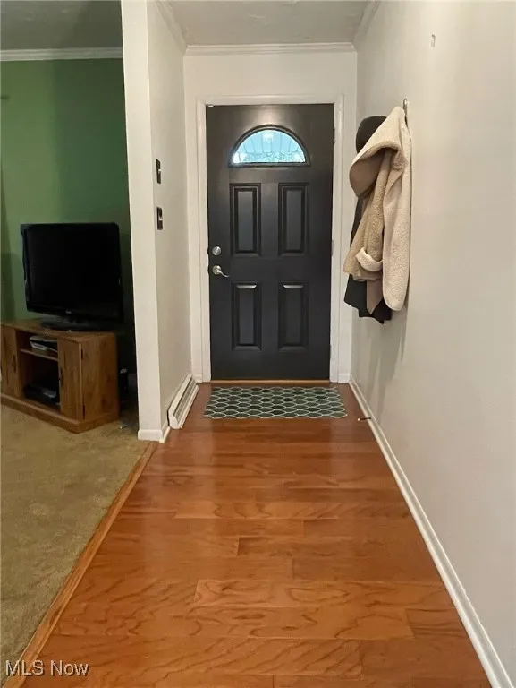 Foyer with steel entry door, crown molding and hardwood flooring.