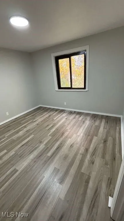 Unfurnished room with wood finished floors and baseboards