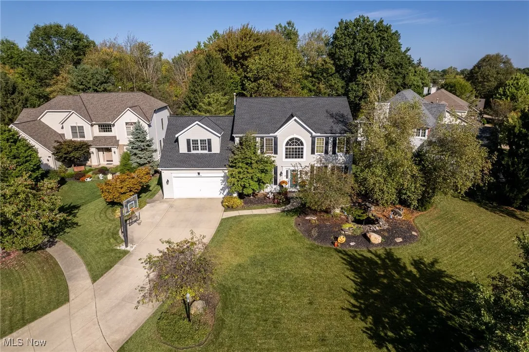 View of front of property featuring concrete driveway, a front yard, an attached garage, and a shingled roof