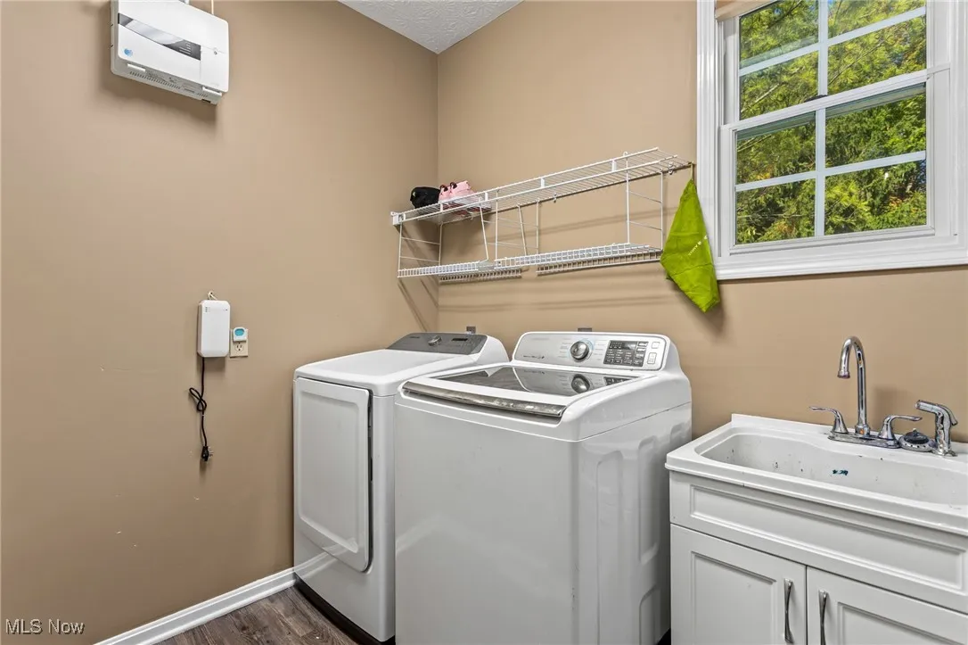 Laundry area with independent washer and dryer and dark wood-type flooring