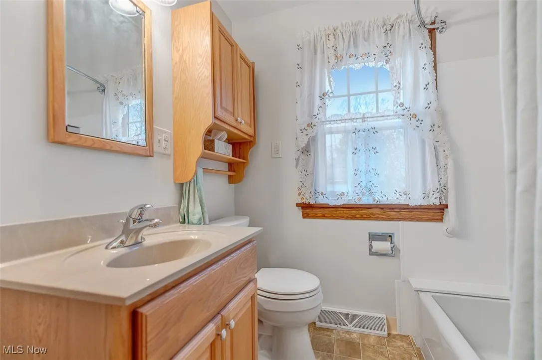 Full bath featuring vanity, light tile patterned floors, and shower / bathtub combination with updated fixtures
