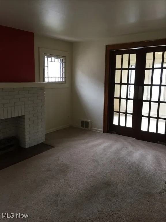 Unfurnished living room featuring carpet and a brick fireplace