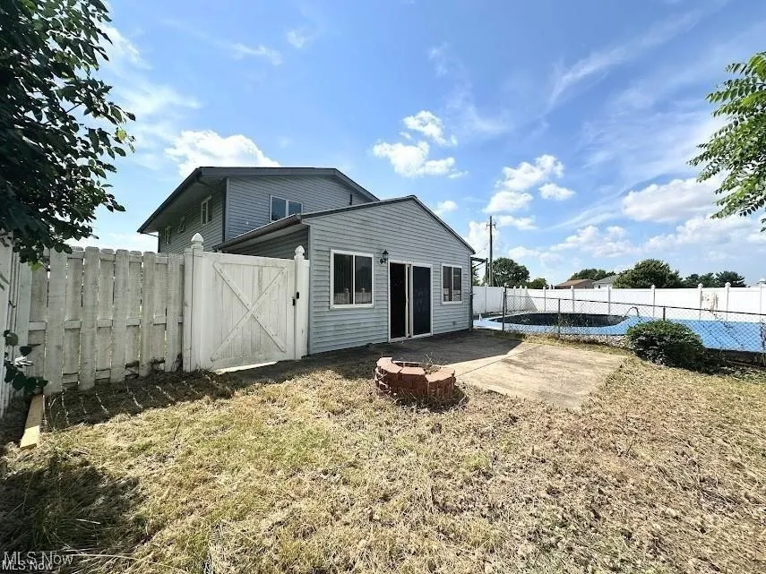 Rear view of house featuring a patio area, a gate, a fenced backyard, and a fire pit
