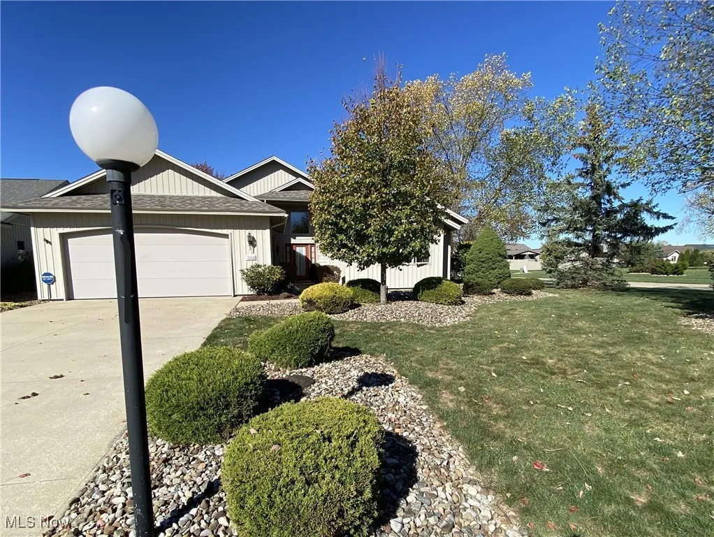 View of front facade featuring a garage, a front yard, driveway, and a shingled roof