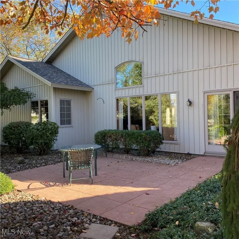 Back of house featuring a patio area, a shingled roof, and board and batten siding