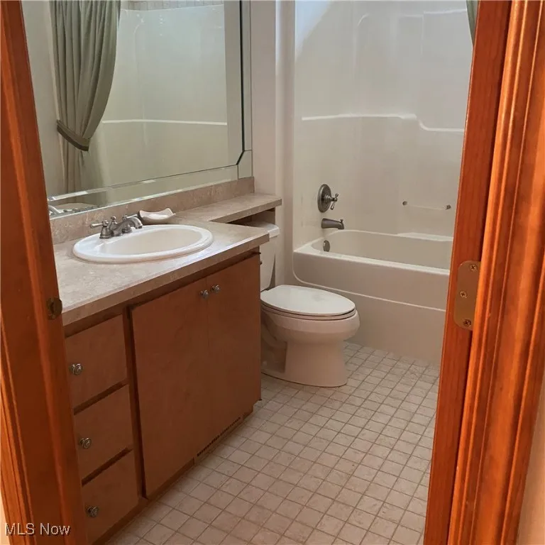 Full bath with vanity, light tile patterned floors, and tub / shower combination