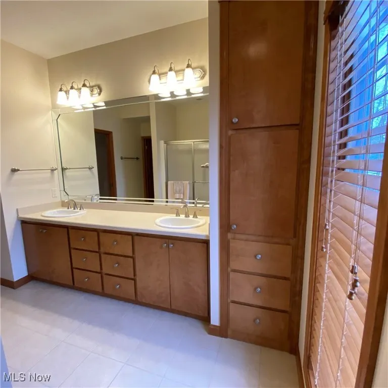 Master Full bath with double vanity, a stall shower, and light tile patterned flooring